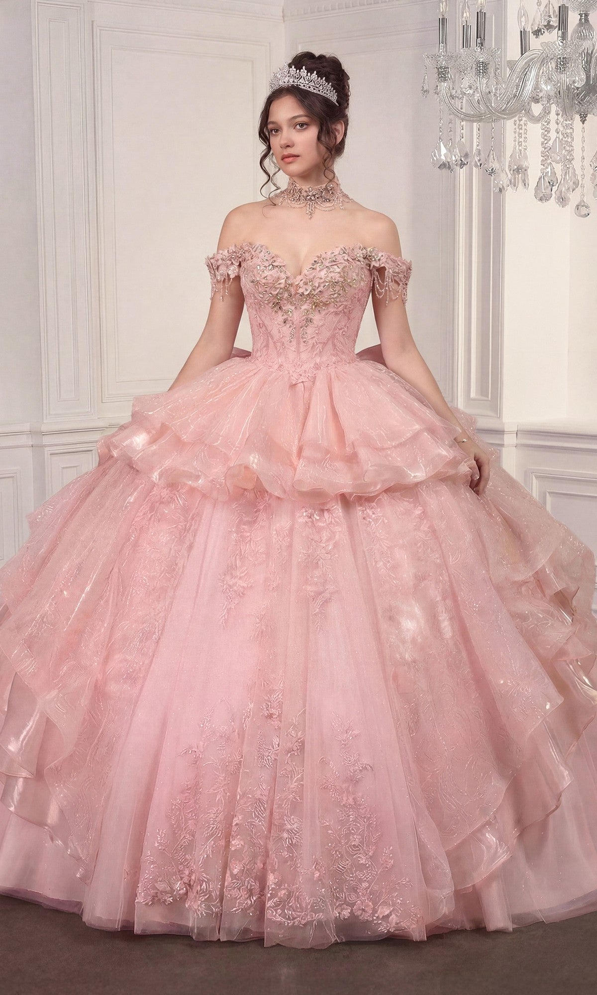 A woman stands in an elegant room wearing the Quinceanera Dress 15742 By Ladivine in pink, featuring an elaborate off-the-shoulder design with floral details and a tiara.